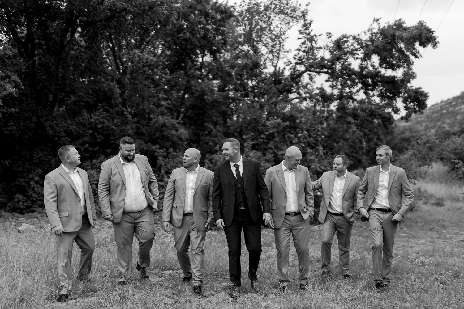 Black and white portrait of groomsmen and groom standing in casual formation outdoors.