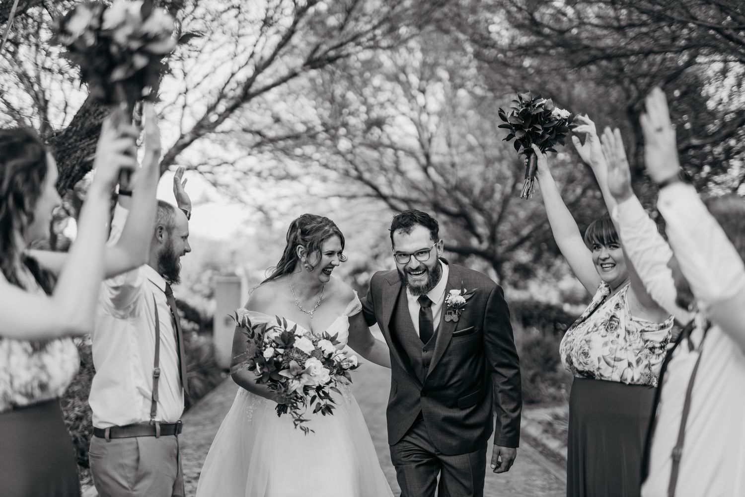 A black and white photo shows guests creating a celebratory arch with raised arms for the newlyweds.