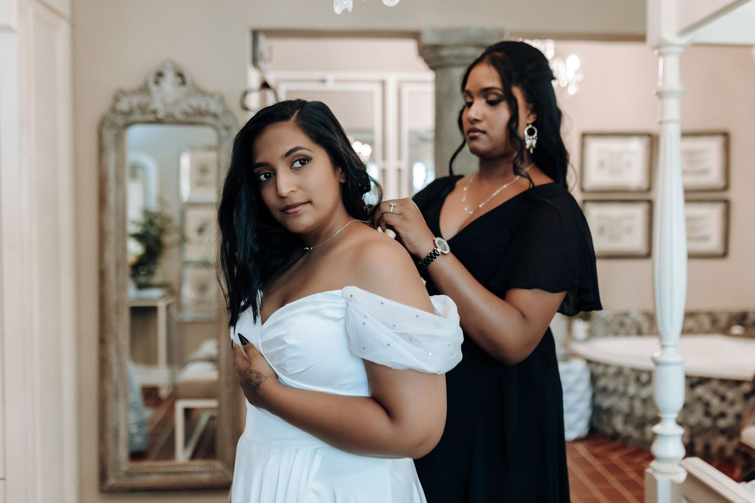 Wedding preparation scene showing final dress adjustments in an elegant room.