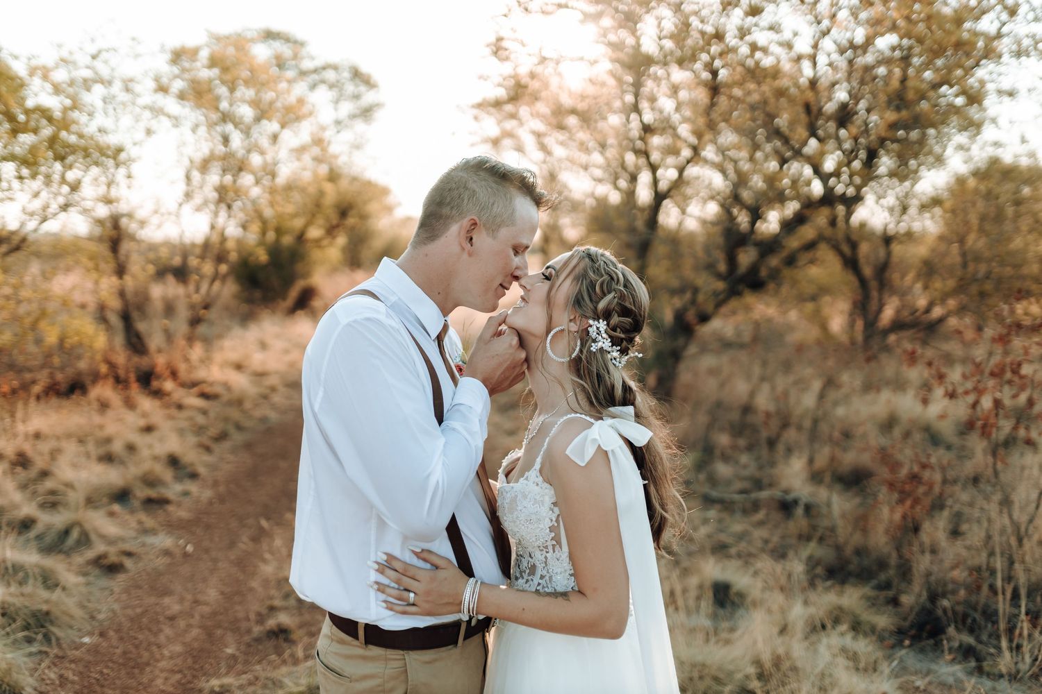 Couple sharing intimate moment during sunset photoshoot in rustic outdoor setting.