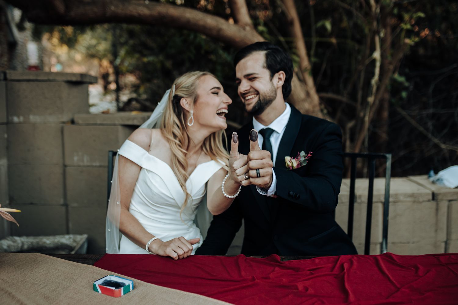 Happy wedding couple sharing joyful laughter at their reception table.
