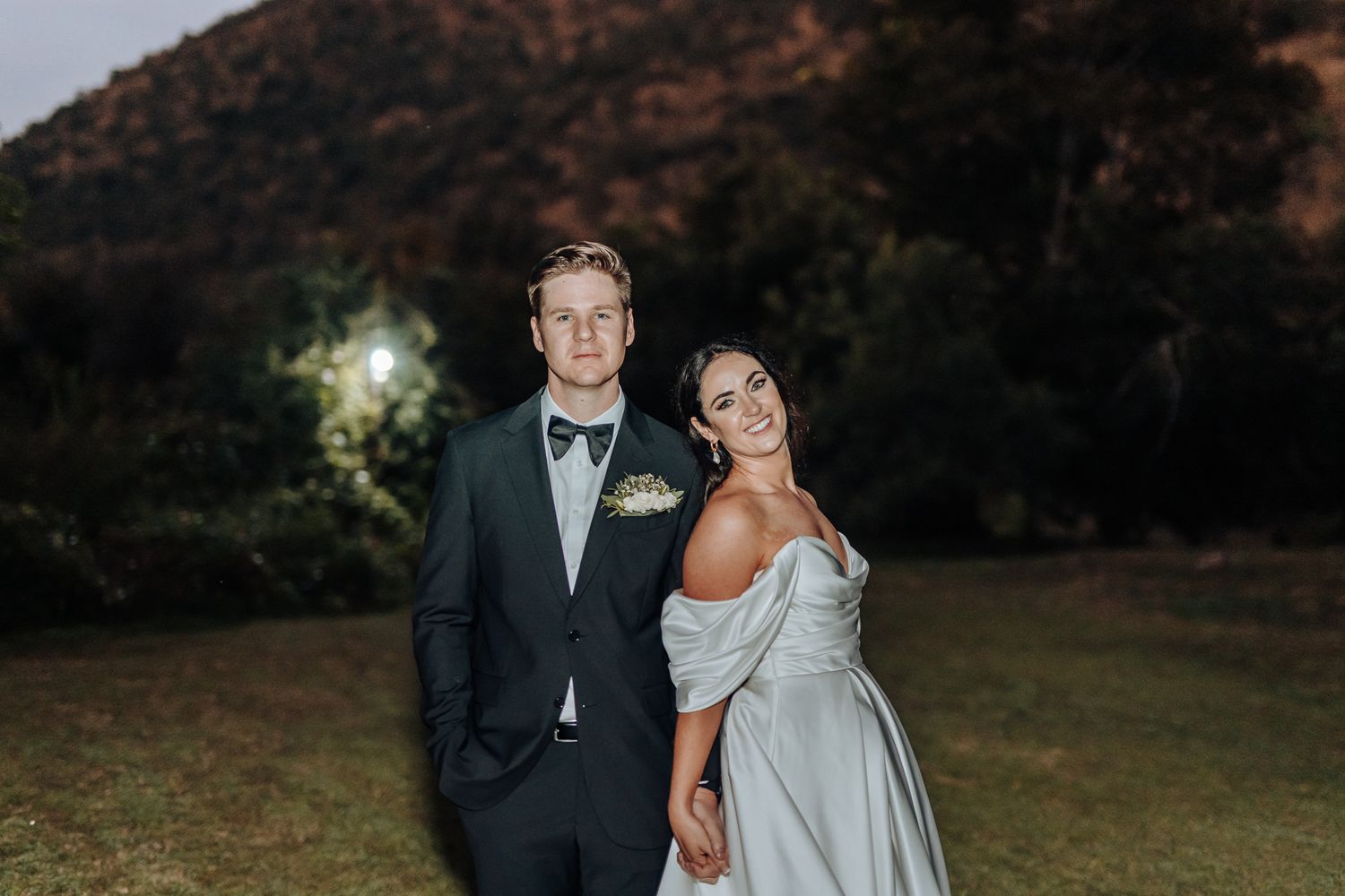 A twilight wedding portrait with mountain backdrop and soft evening lighting.