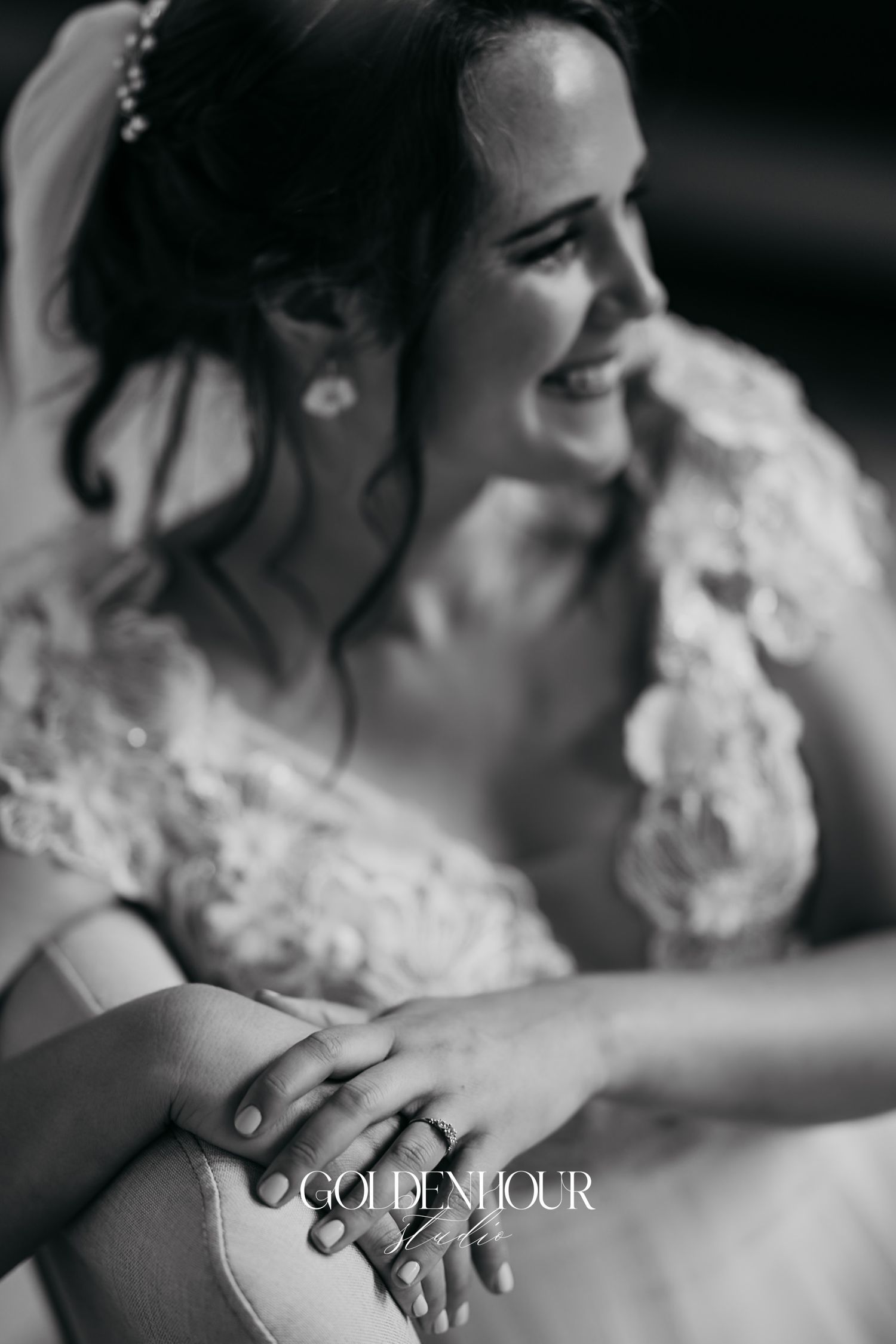 Black and white portrait of a smiling bride in lace wedding dress with delicate hair accessories.