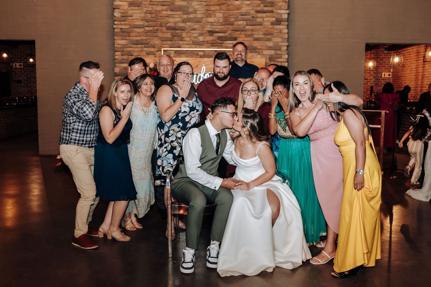 Wedding reception guests enjoying the dance floor in a modern brick-walled venue.