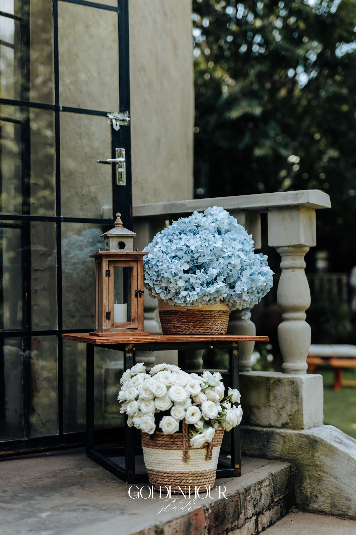 Elegant white hydrangea flower arrangements displayed on stone ledges beside glass windows at a wedding venue.