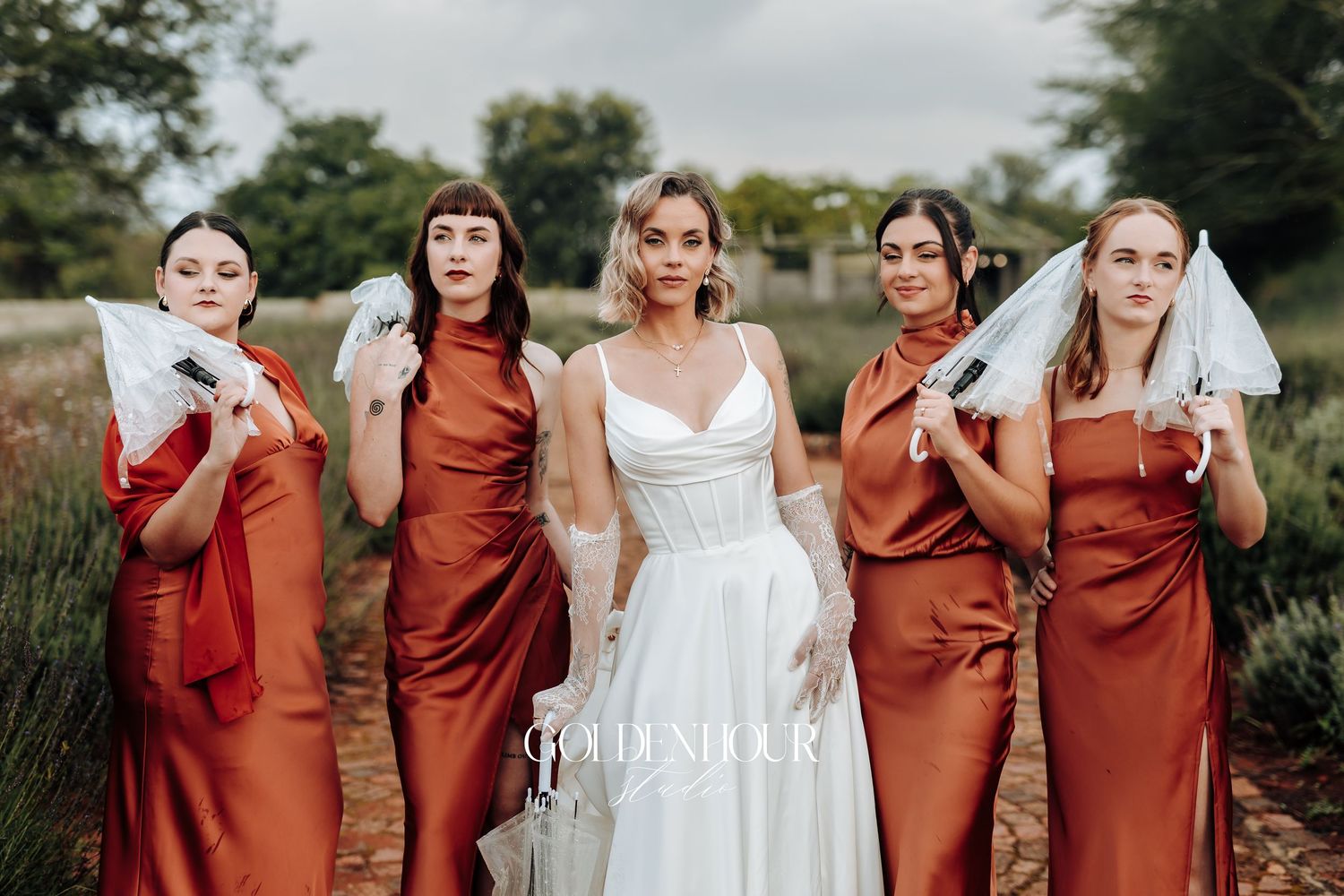 Wedding party in burgundy dresses poses playfully for group photos outdoors.