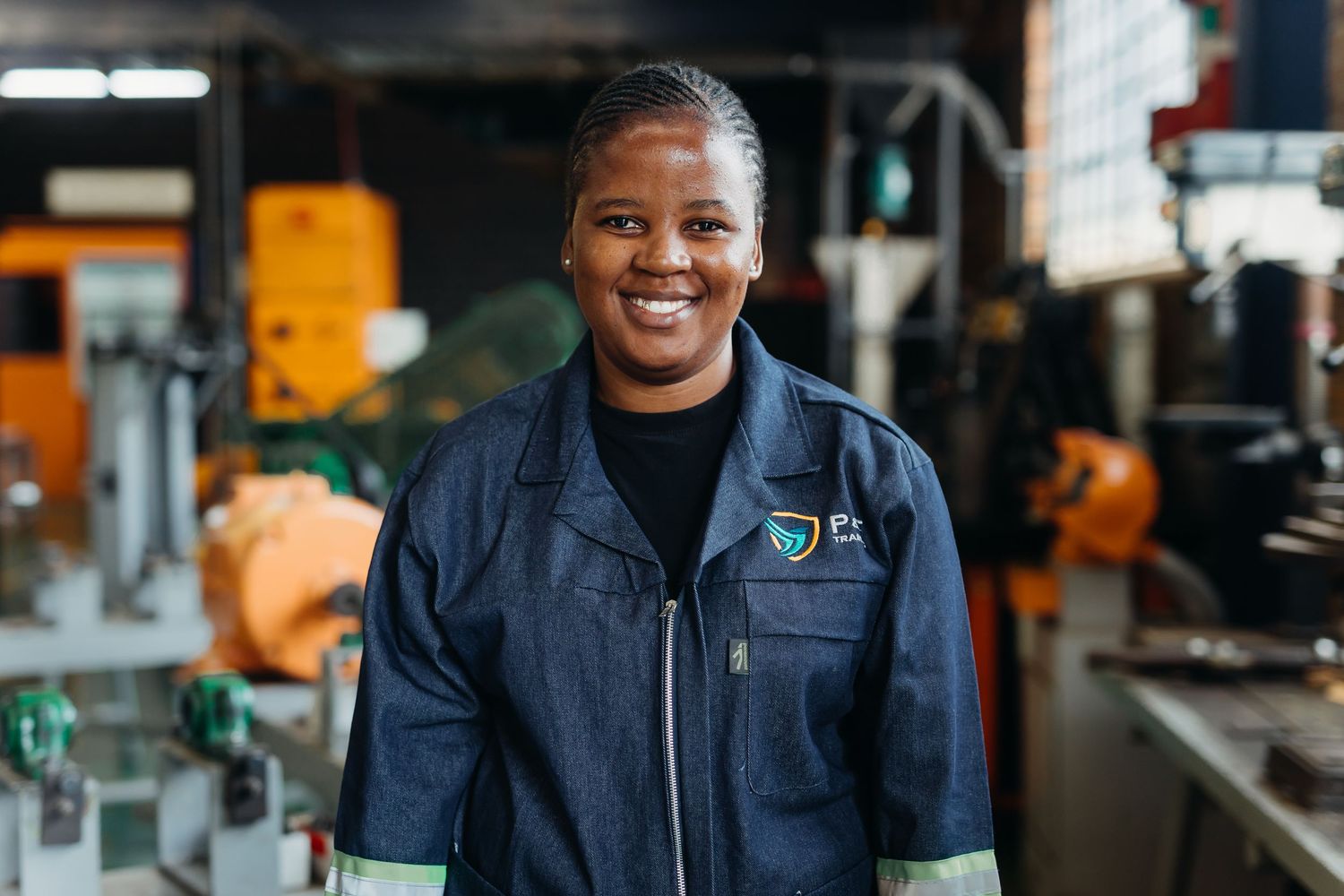 Workers in navy blue uniforms smiling while working at a manufacturing facility.