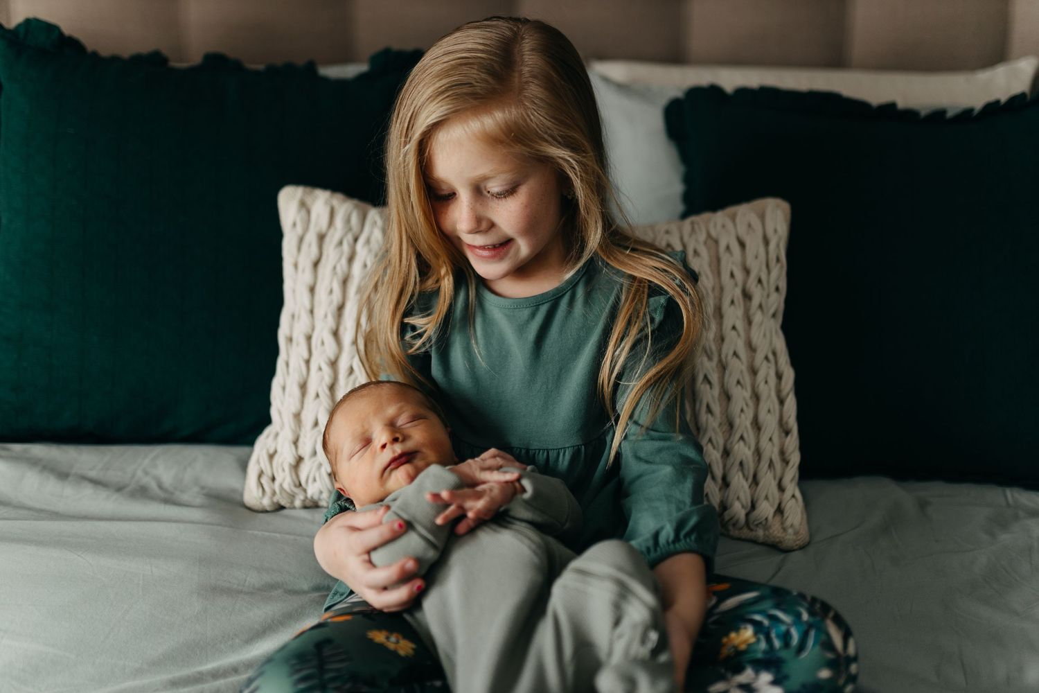 A warm tender moment captured on a couch with knitted decorative pillows in sage green tones.