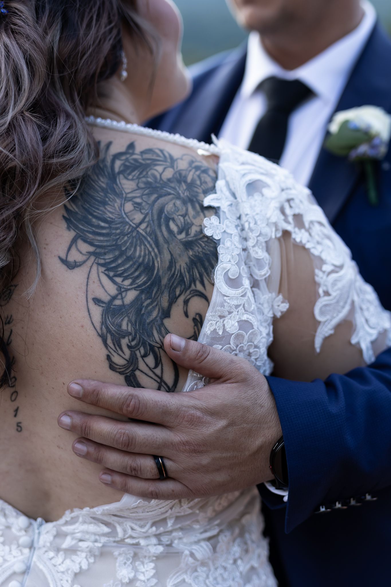Close-up of ornate lace wedding dress details and decorative back tattoo.