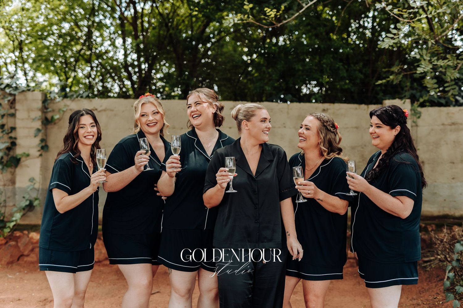 A group wearing matching navy blue outfits laughs together outdoors during a casual photo session.