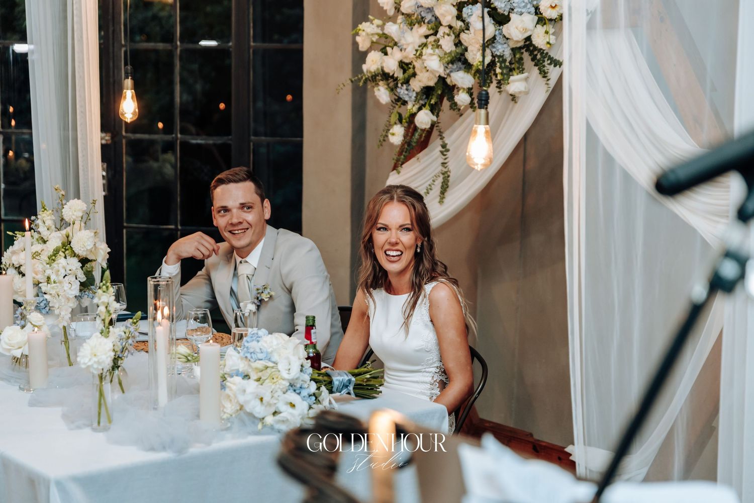 Wedding reception table setup with elegant decor and lighting in an indoor venue.