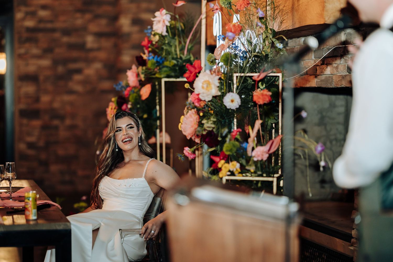 Wedding celebration in a rustic brick venue with colorful floral arrangements and decorative elements.