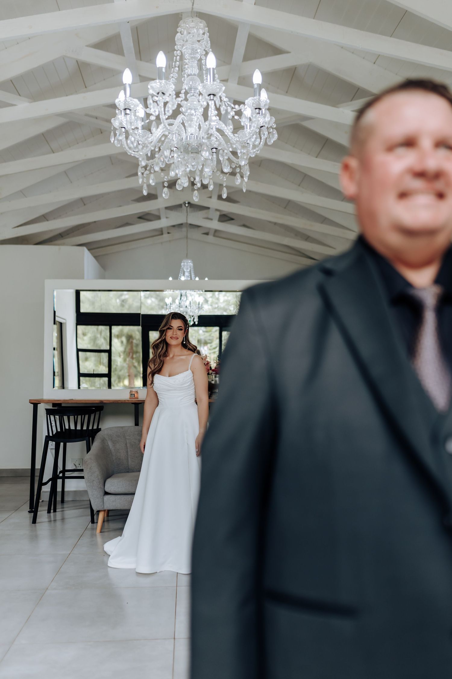 Wedding scene in modern venue with crystal chandelier showing white dress and dark suit in motion.