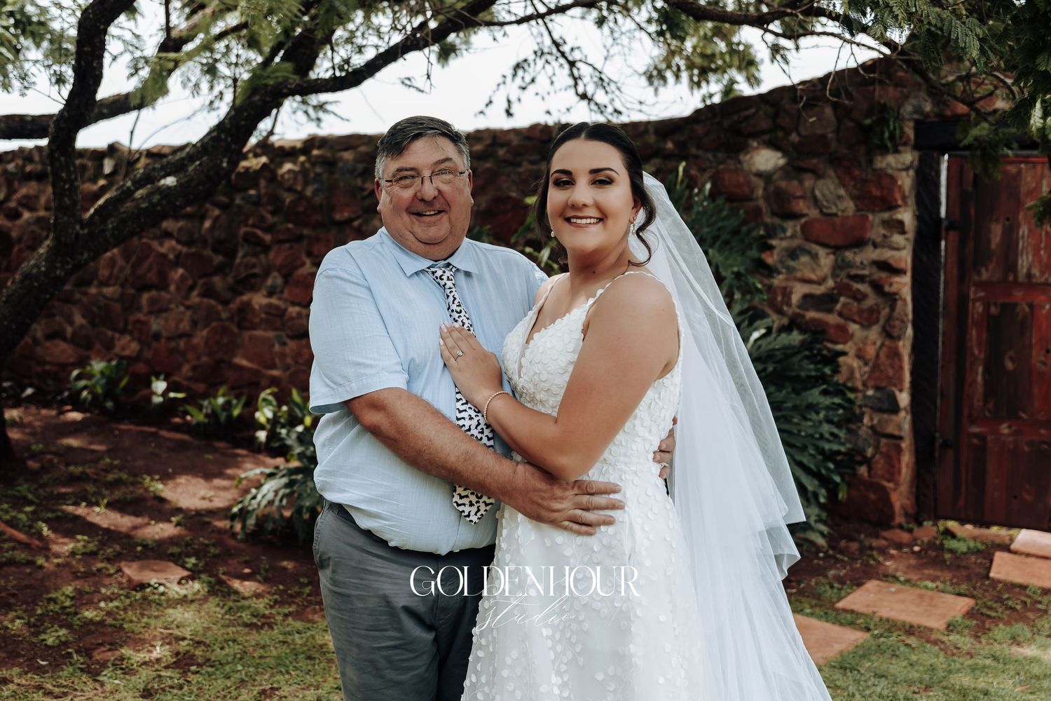 Wedding couple sharing a joyful moment outdoors with natural greenery in the background.
