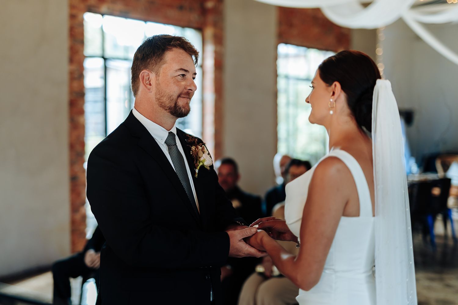 A wedding couple shares intimate moments during their ceremony in an elegant indoor venue.
