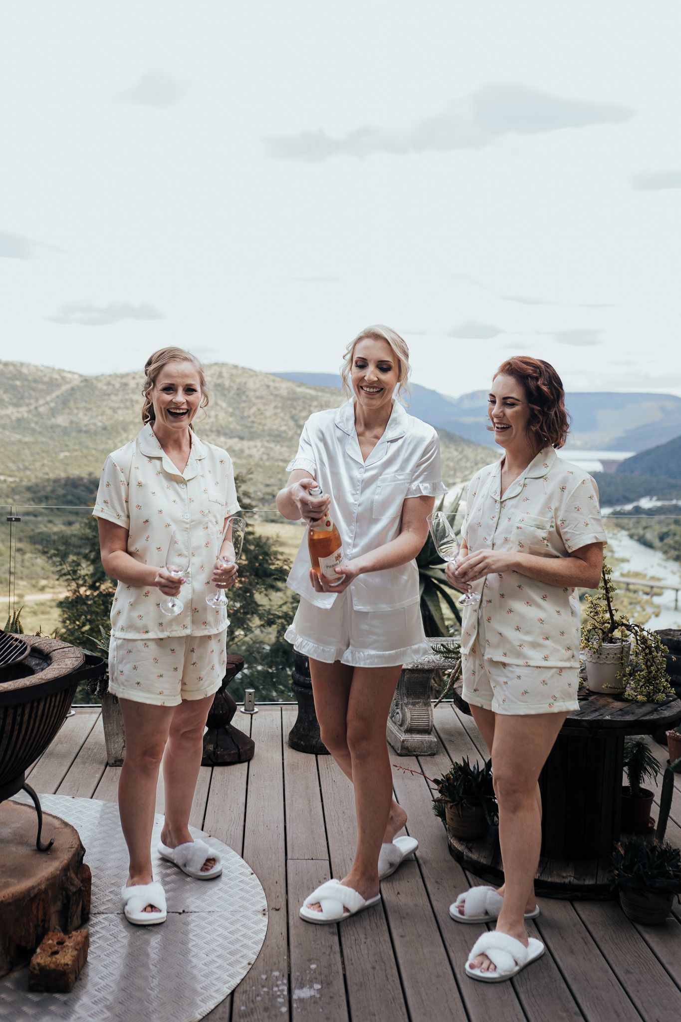 Group wearing matching white sets and slippers chatting on mountain view deck.