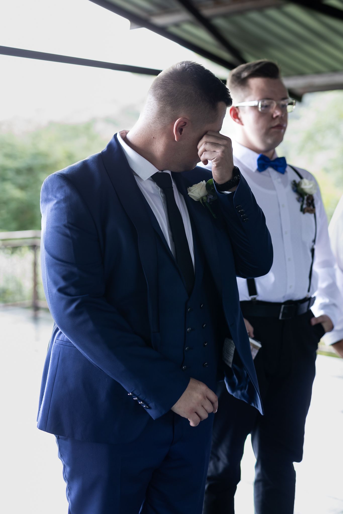Emotional moment captured during outdoor wedding ceremony with formal attire.