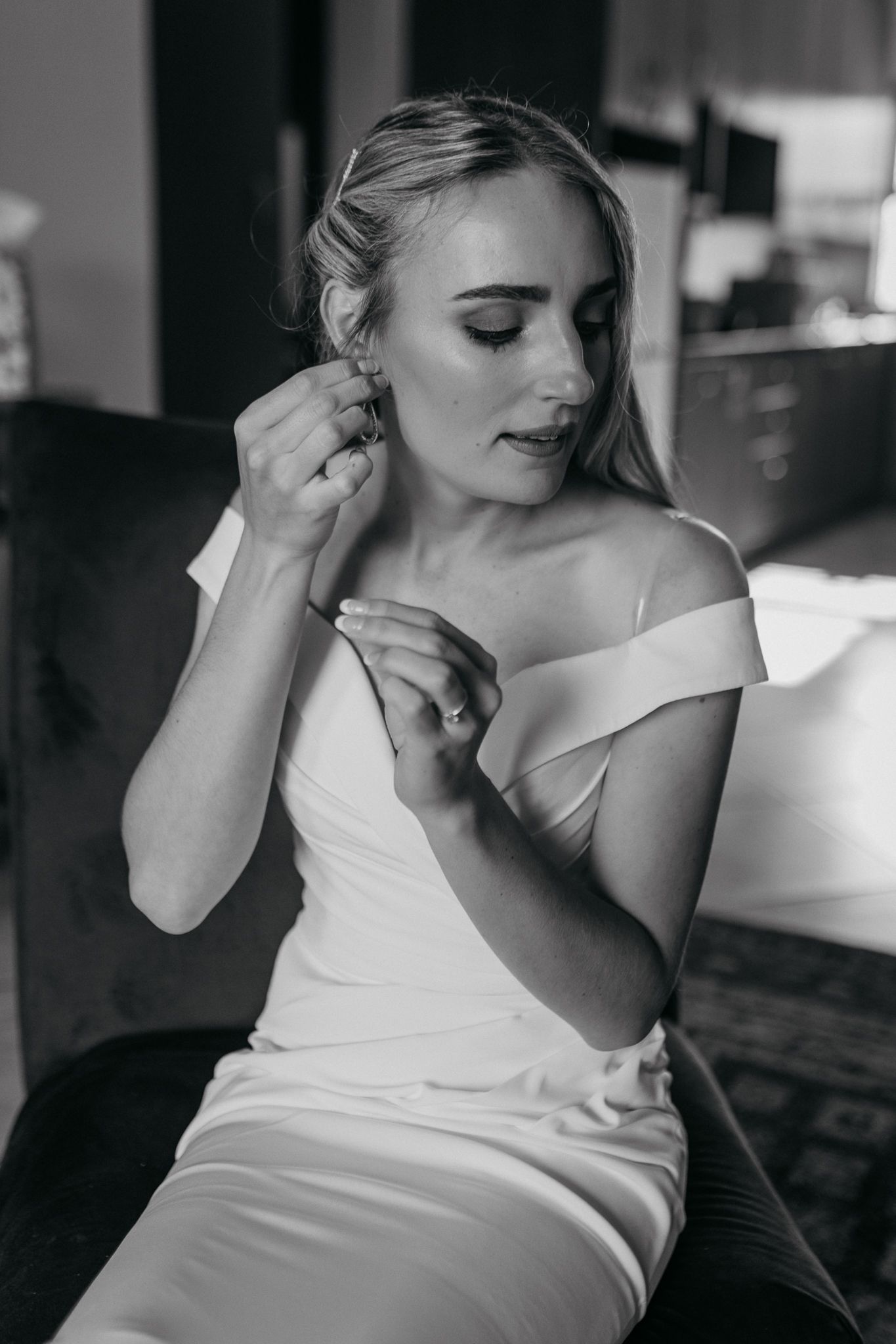 Elegant bridal portrait showing off delicate jewelry and off-shoulder white dress.
