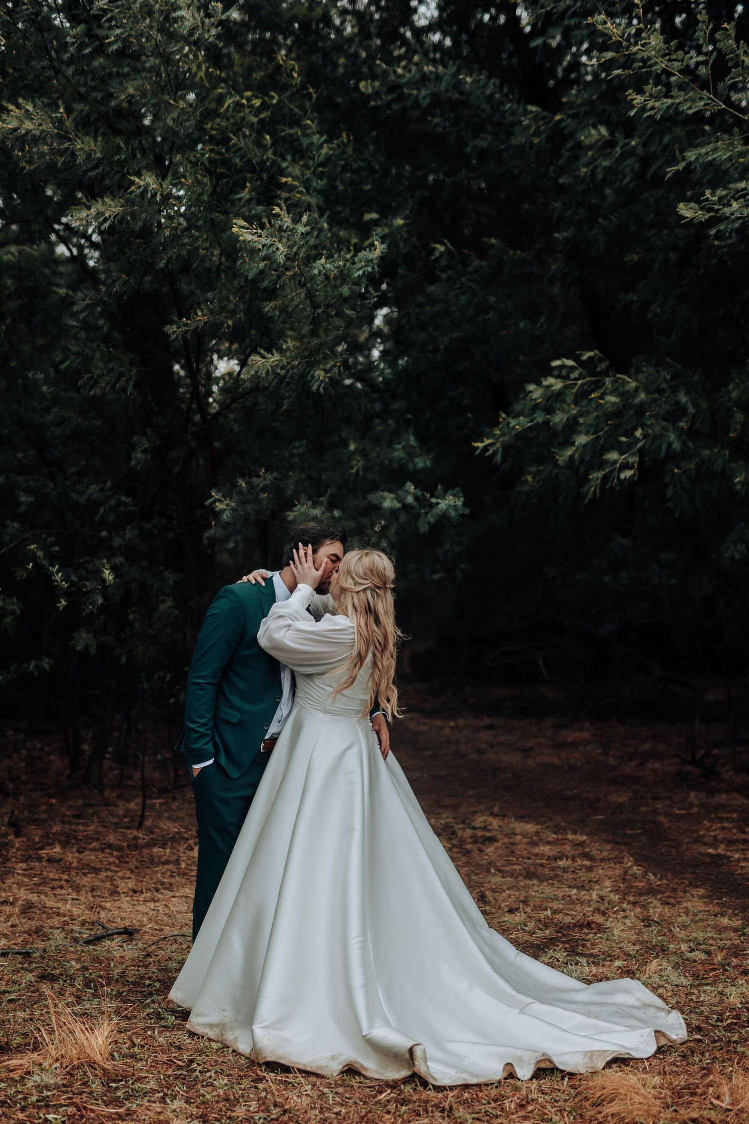 A romantic wedding portrait shows the couple embracing in a wooded setting.
