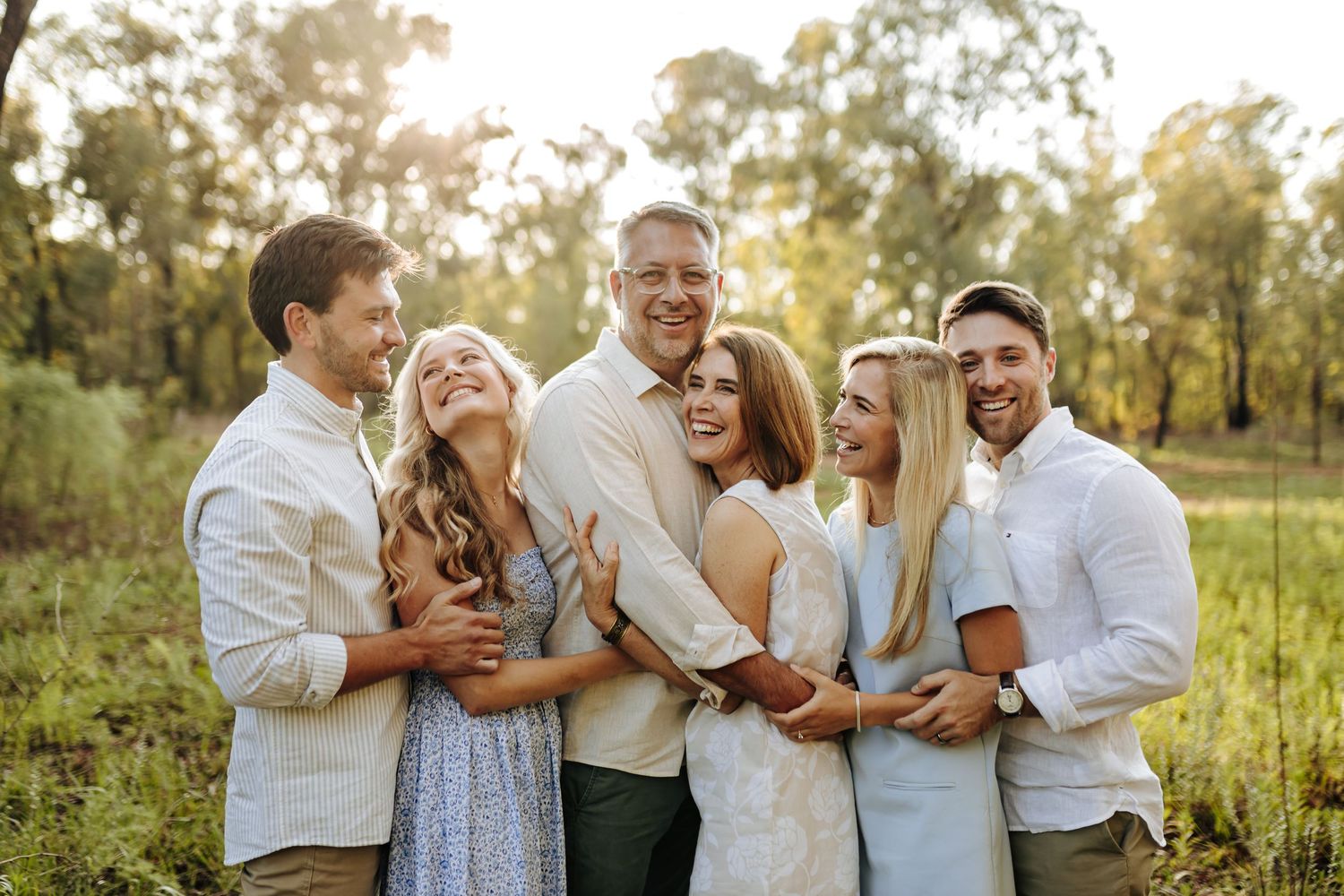 A happy family shares joyful moments together while wearing coordinated white outfits during an outdoor photo session.