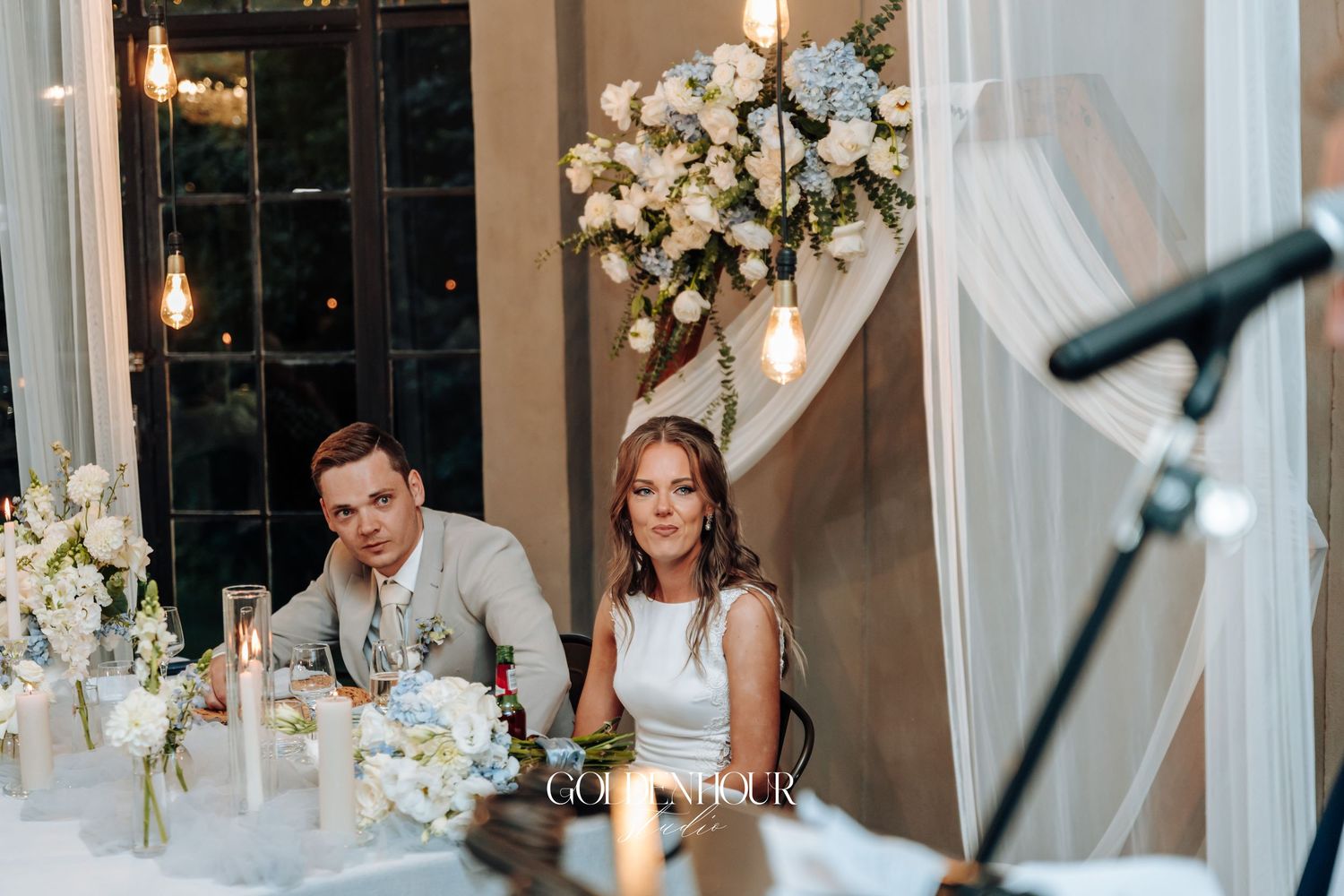 Elegant wedding reception venue decorated with white floral arrangements and crystal chandeliers.