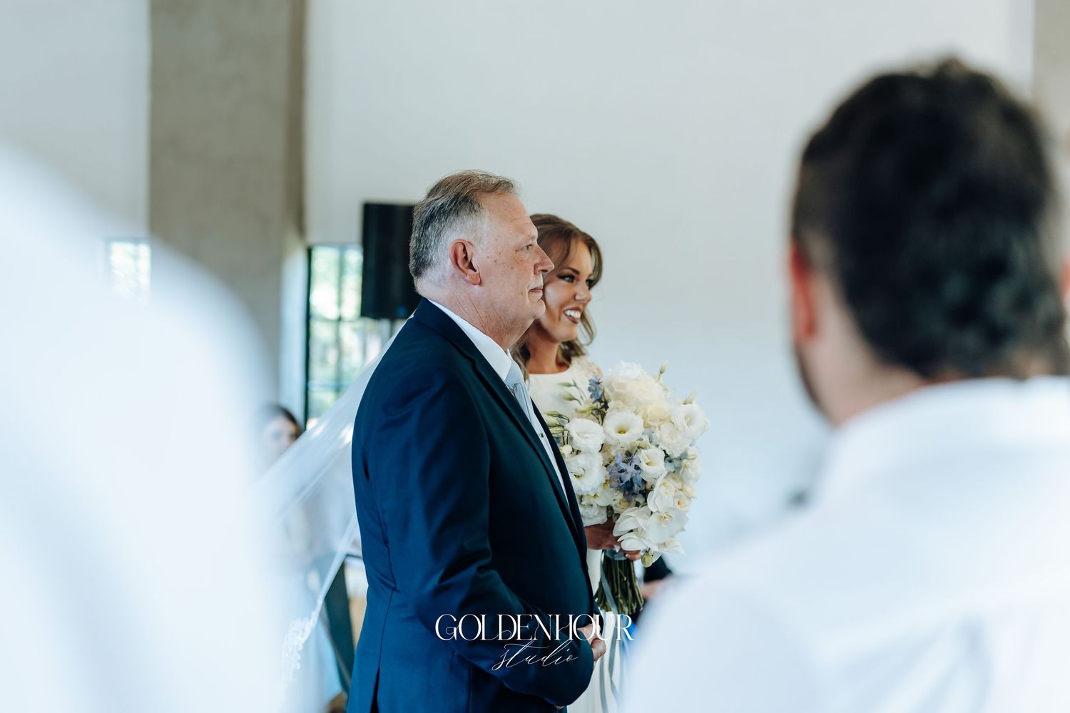 Wedding reception venue with soft natural lighting streaming through windows and white floral arrangements.