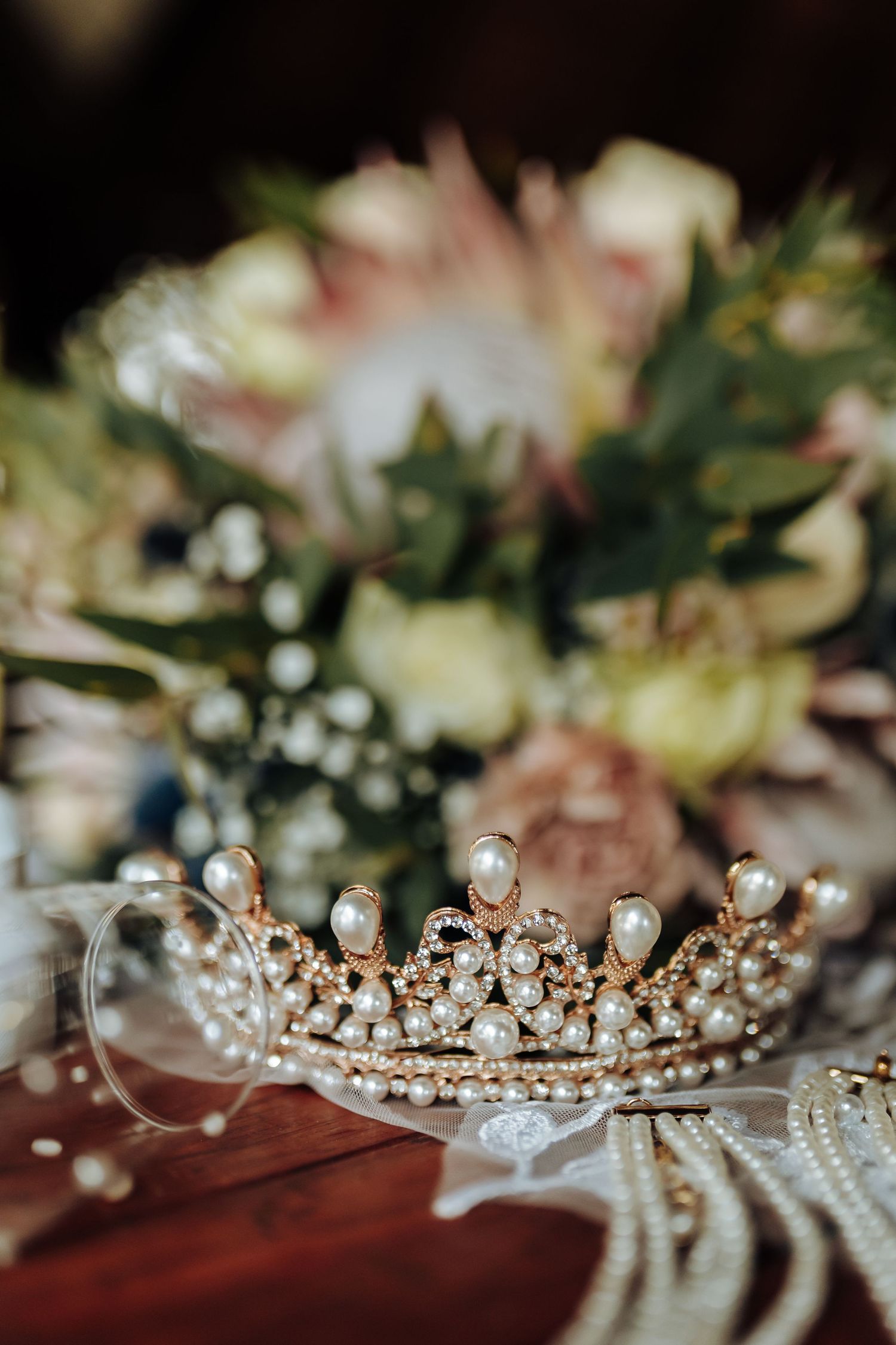 Delicate pearl and crystal bridal tiara with ornate gold details photographed in a sequential closeup view.