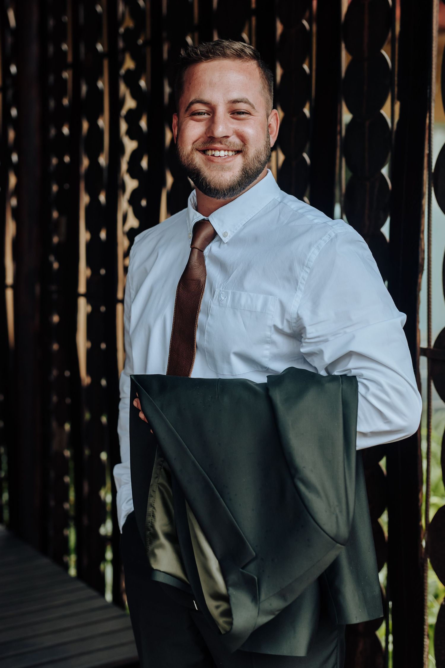 A collage of someone in a white dress shirt and dark tie standing against a black fence background.