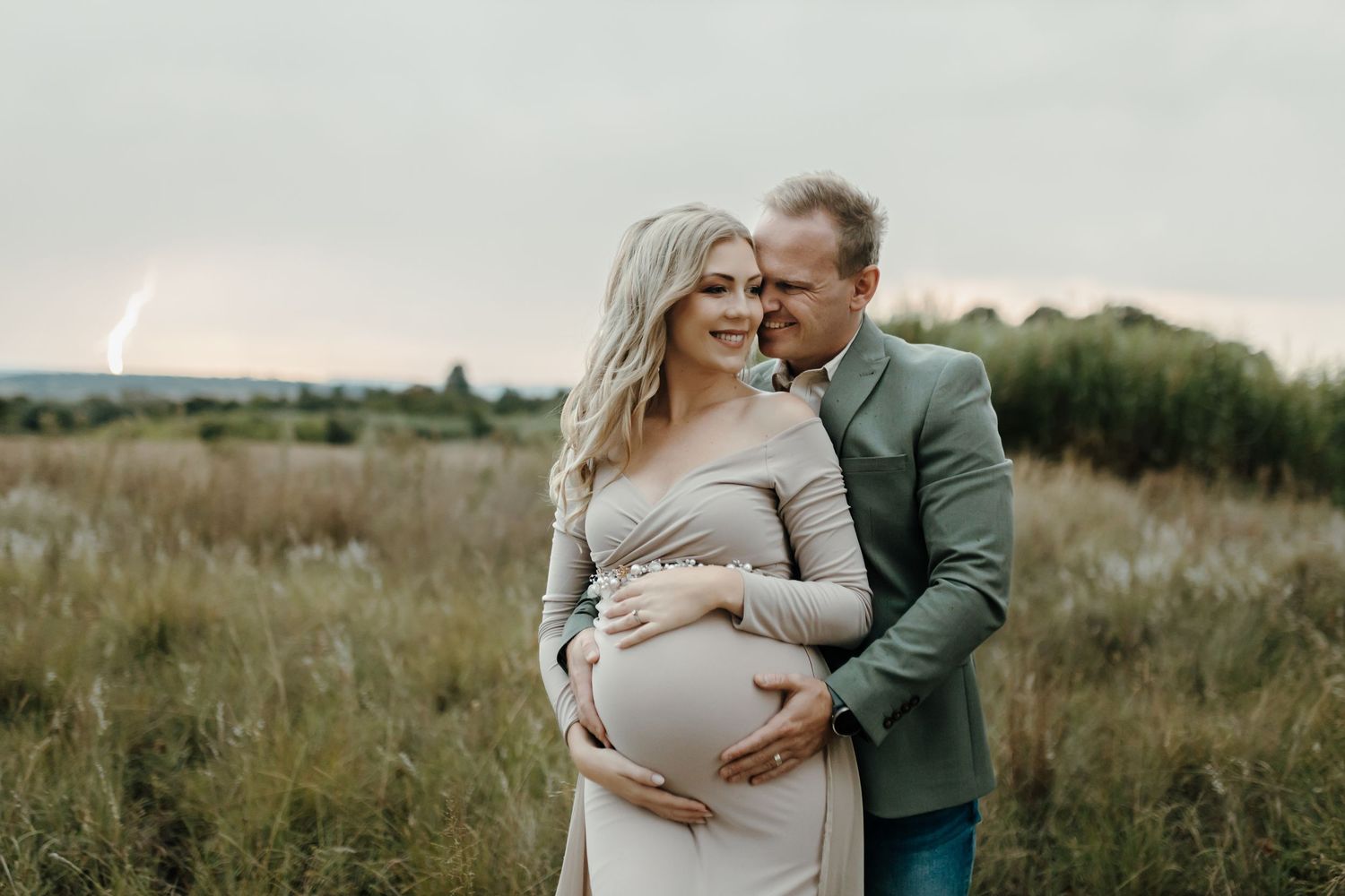 A tender maternity photo session in a natural field during golden hour.
