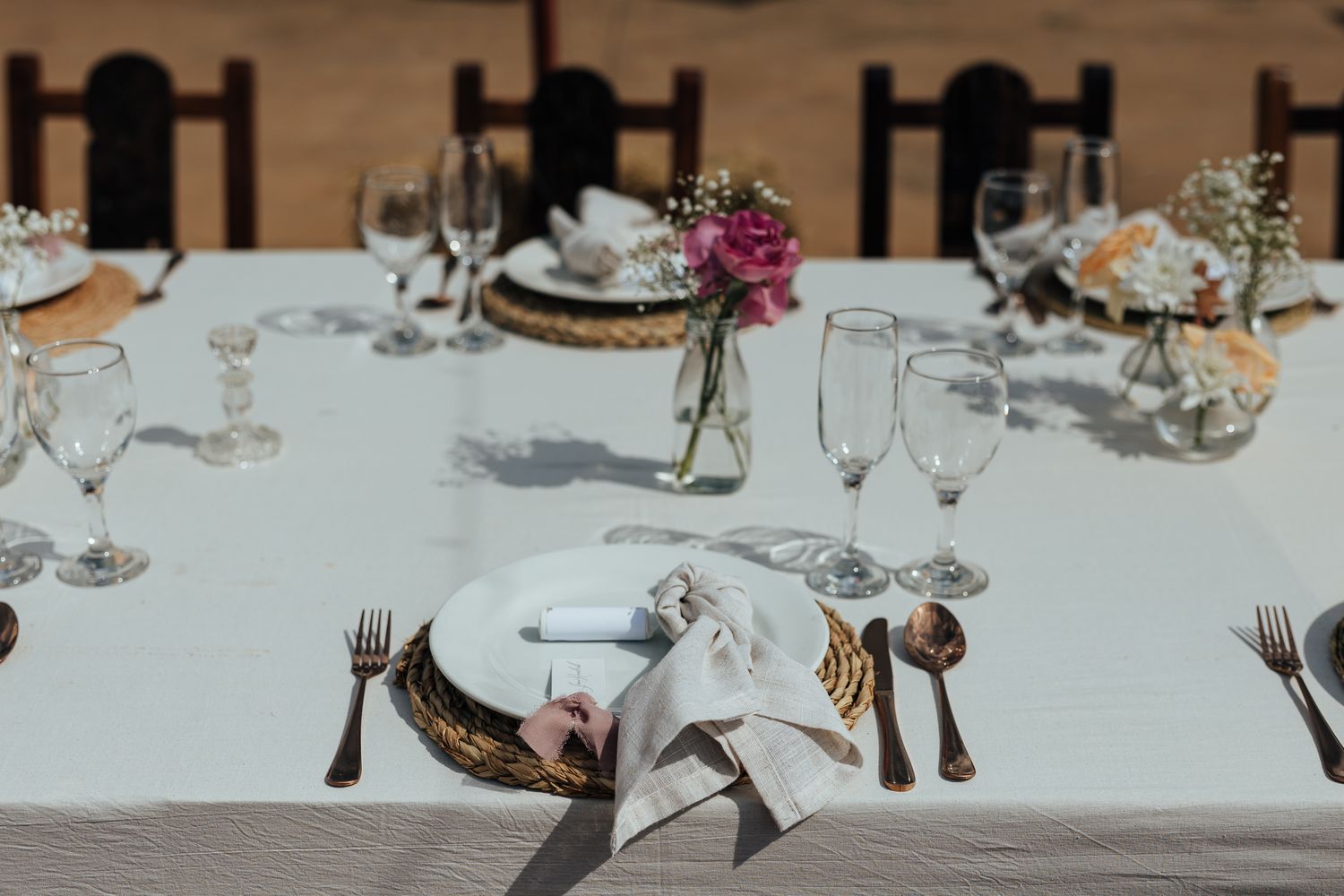 An elegant table setting with white linens, crystal glasses and delicate floral centerpieces.