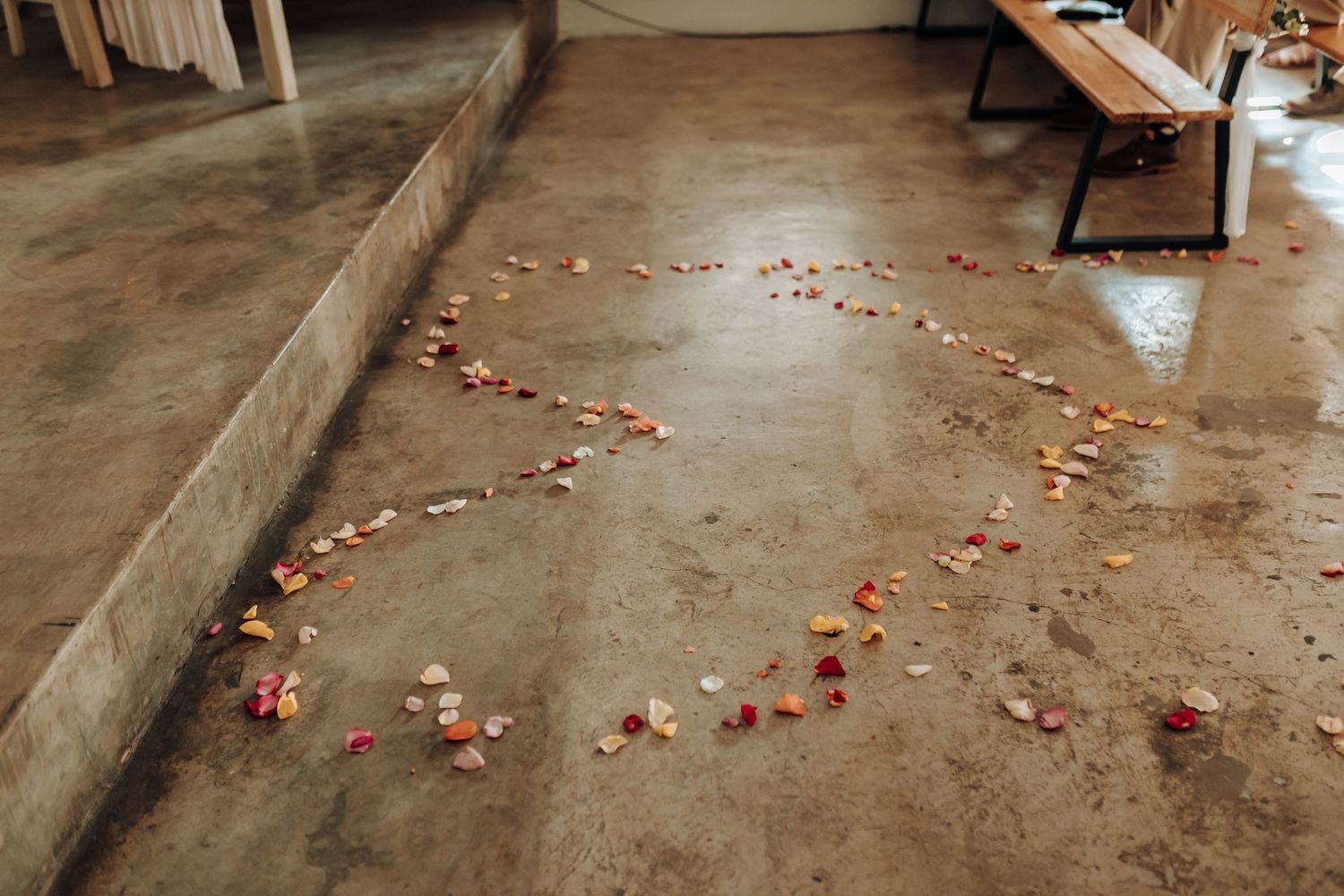 Rose petals arranged in a heart shape pattern on concrete floor at wedding venue.