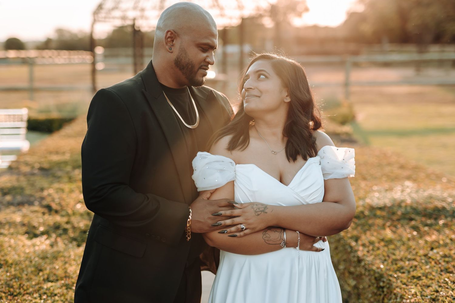 Romantic sunset portrait of couple in wedding attire embracing in outdoor setting.