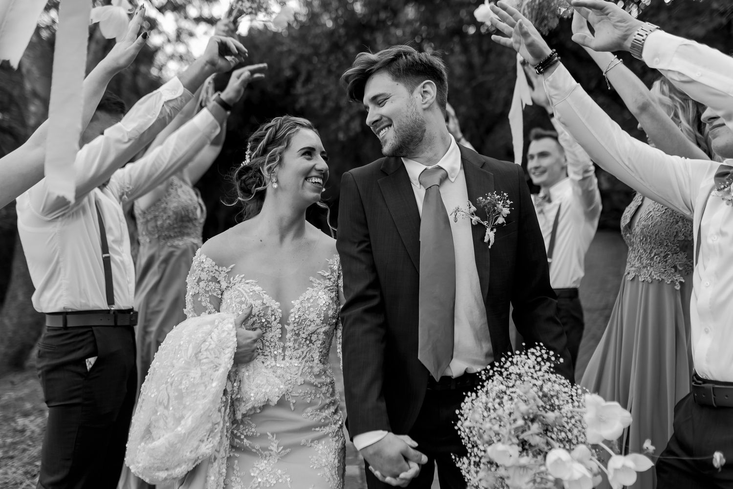 Black and white photo of wedding celebration with guests raising their arms in joyful celebration.