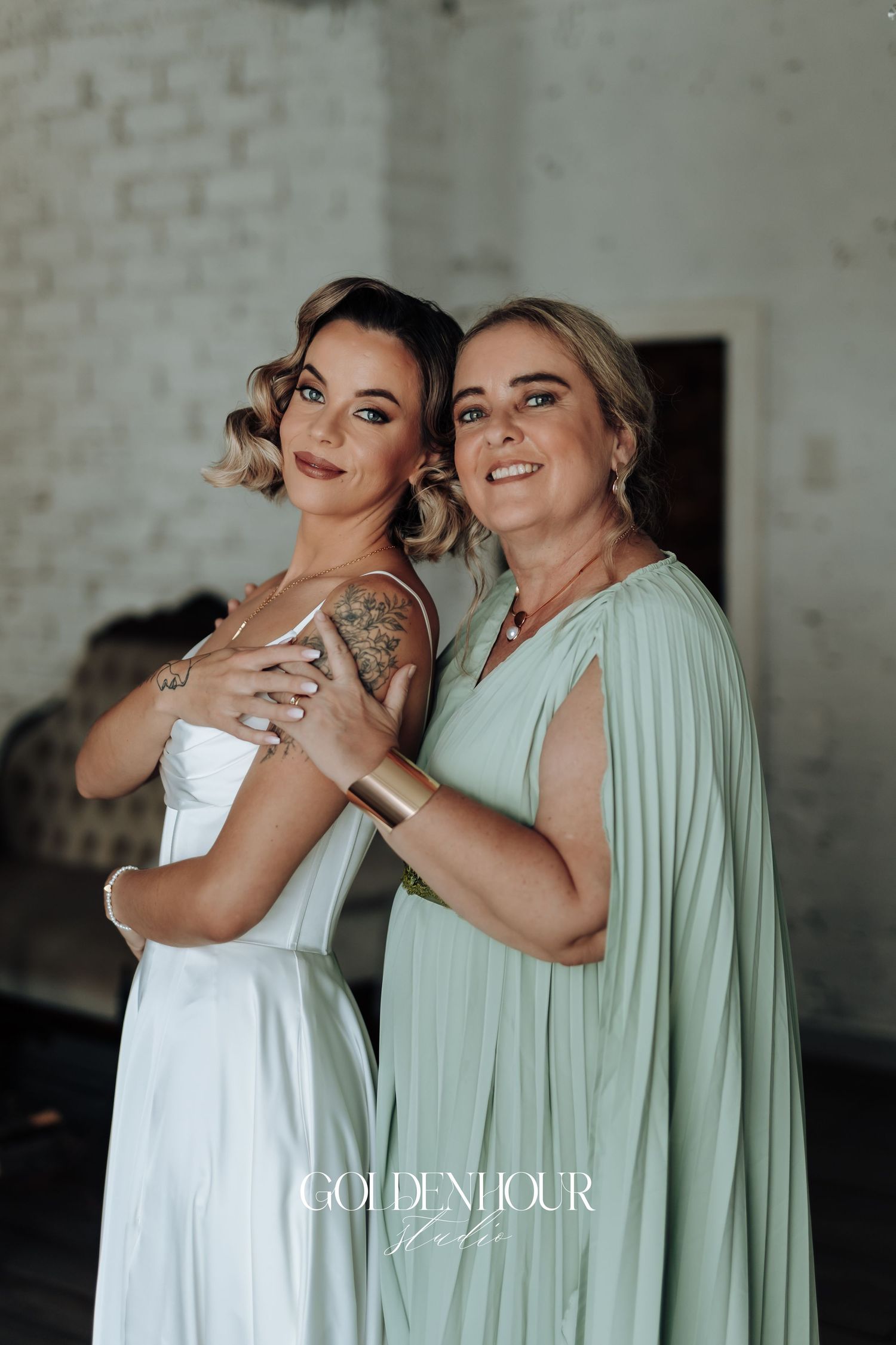 Two bridesmaids share a joyful moment in white and mint green dresses.