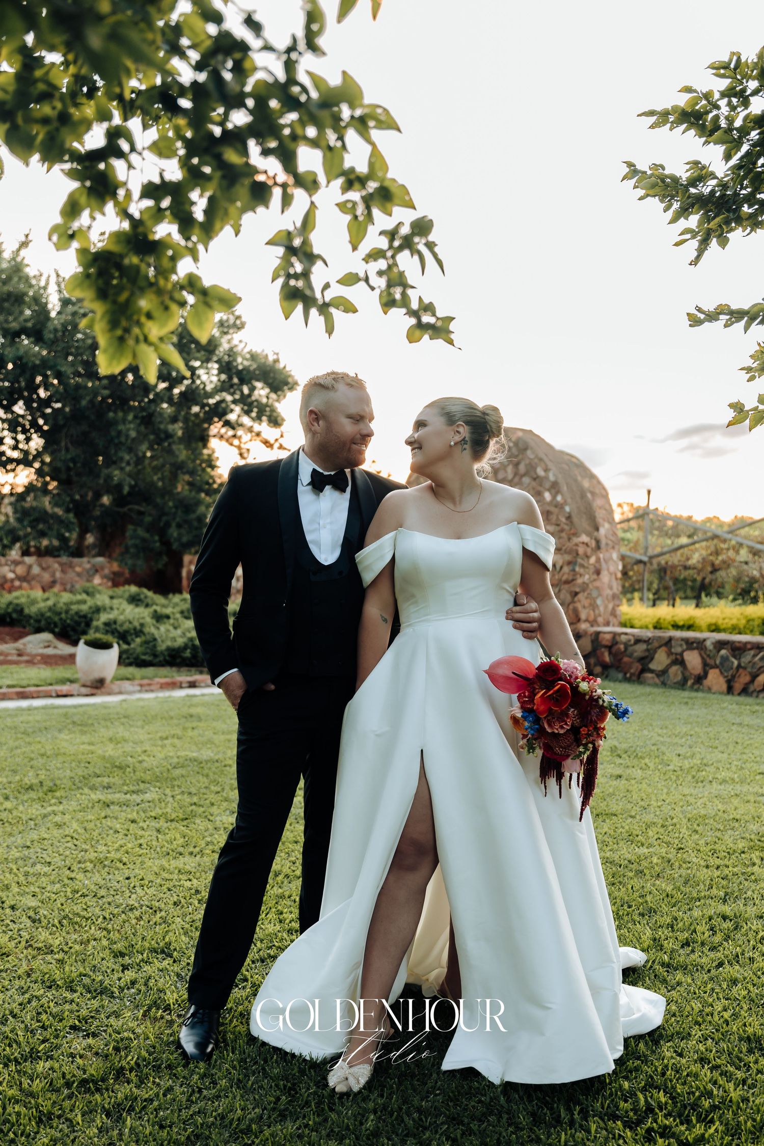 Newlywed couple shares intimate moments on a sunlit lawn during their outdoor wedding photoshoot.