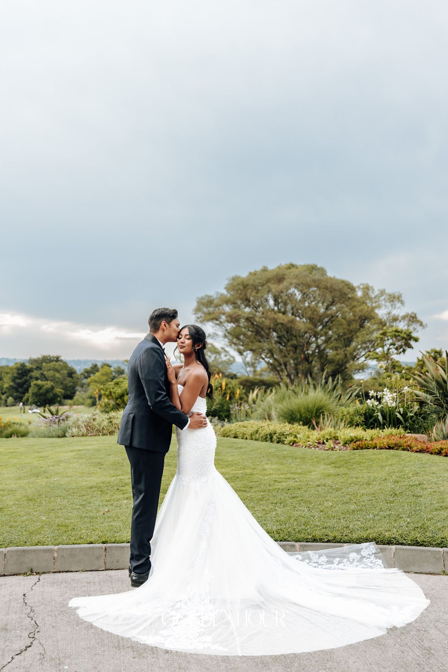 Romantic wedding portrait on manicured lawn with dramatic flowing white dress.