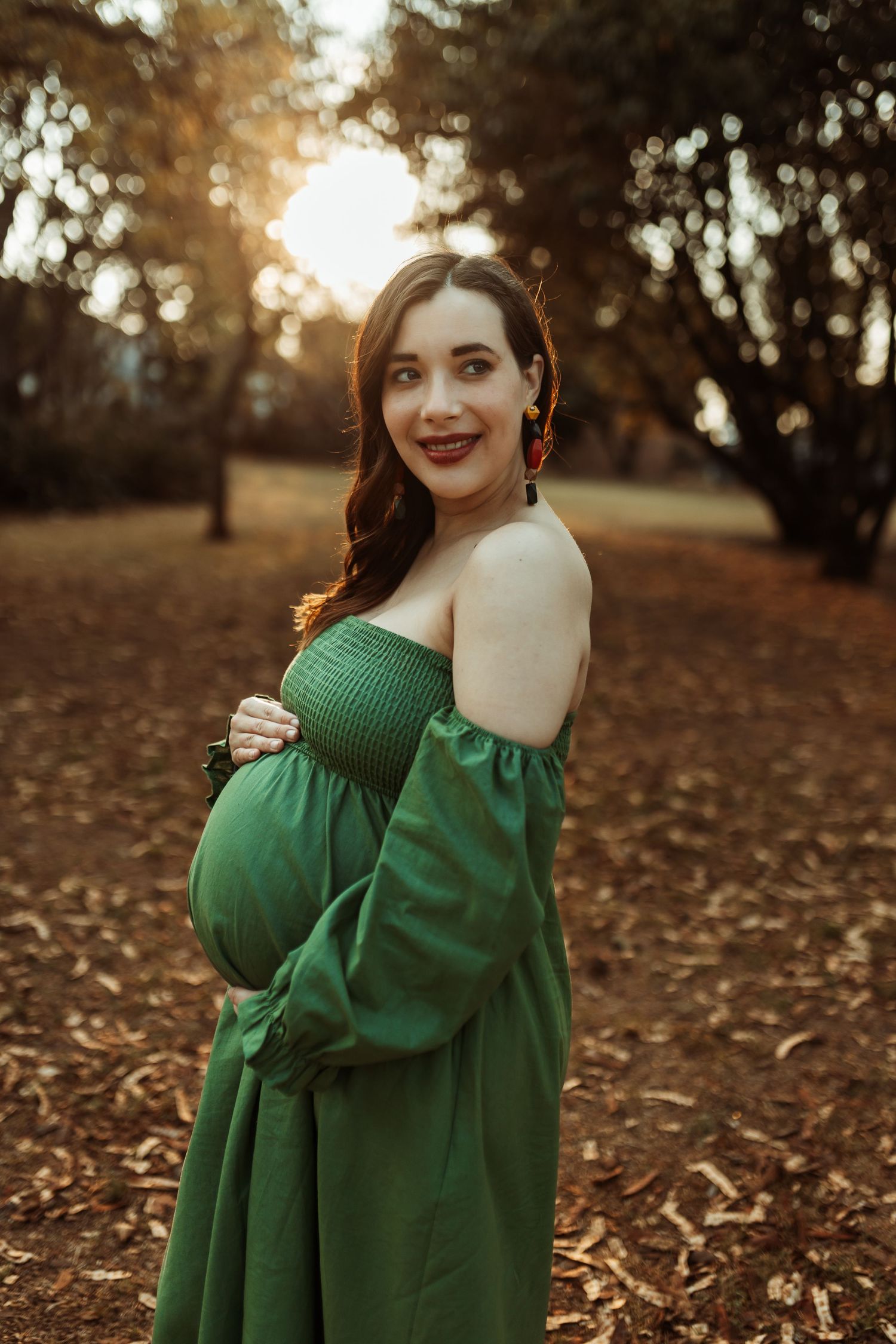 Green sweater dress with puffy sleeves photographed in autumn scenery at golden hour with fallen leaves.