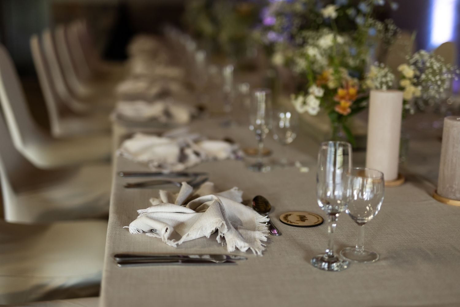 Elegant wedding table setting with white napkins, wine glasses, and delicate floral centerpieces.