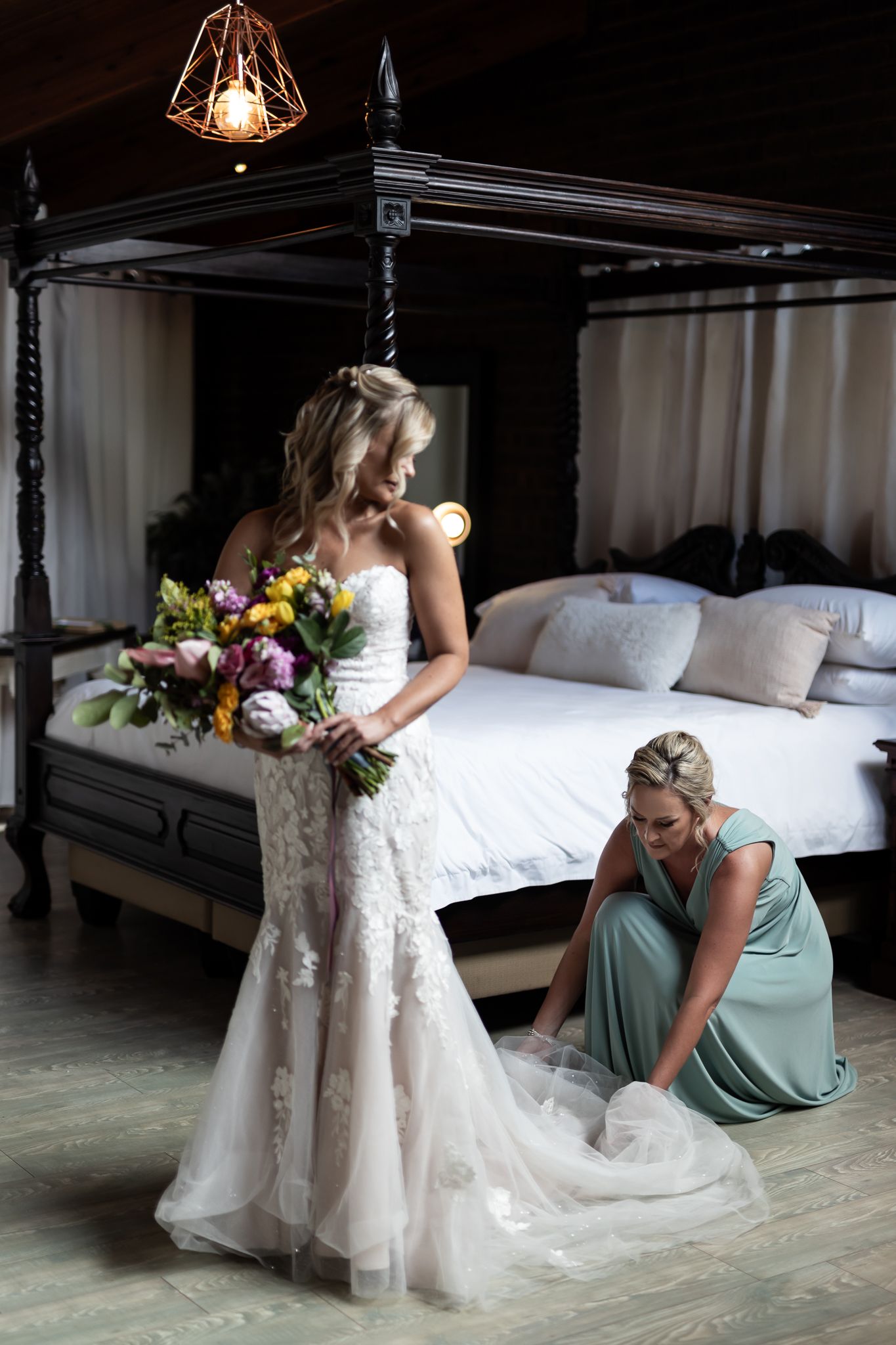 A wedding scene with a stunning lace gown and colorful bouquet next to a four-poster bed.