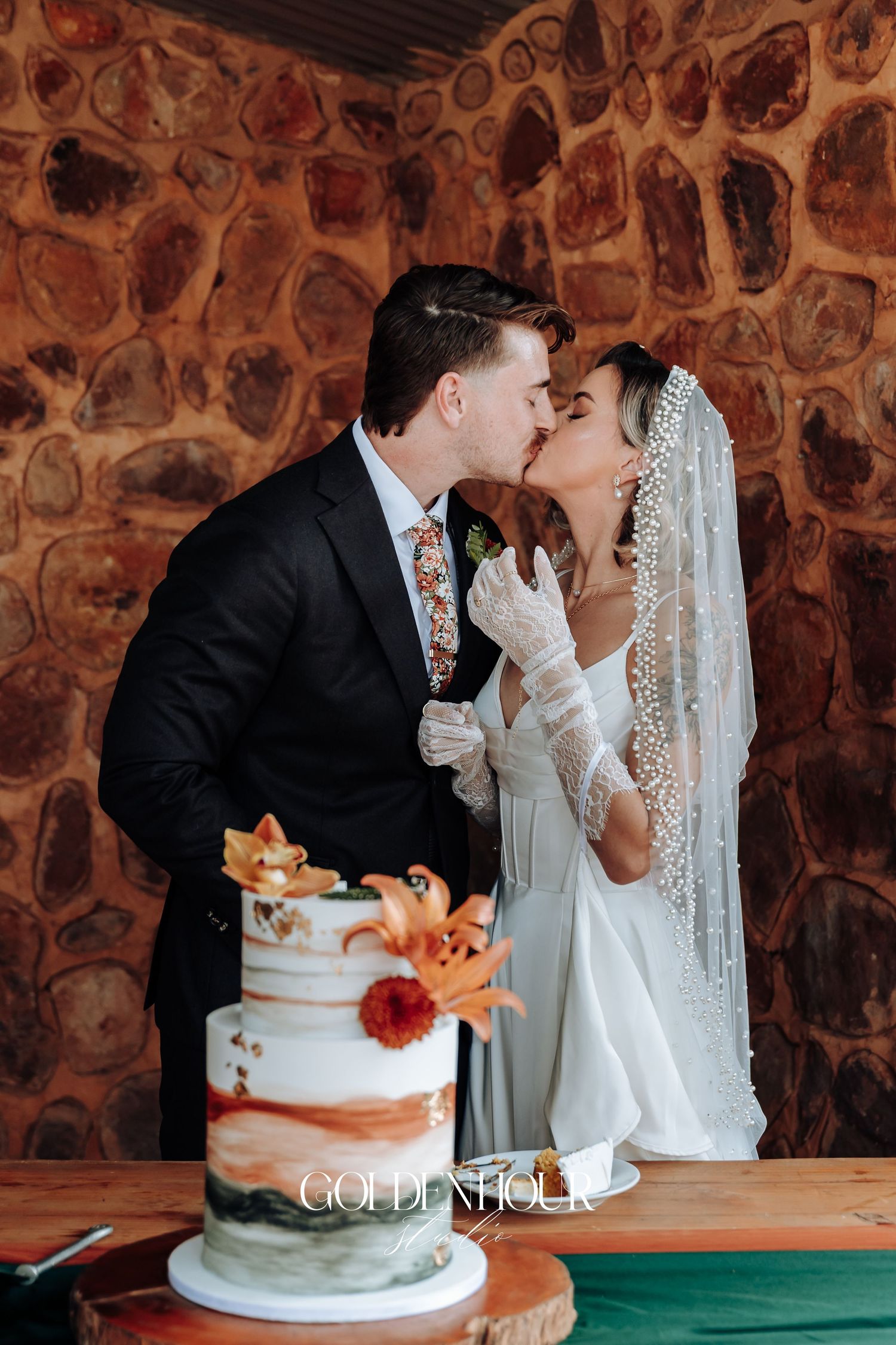 Newlyweds sharing a romantic moment while cutting their copper-accented wedding cake.