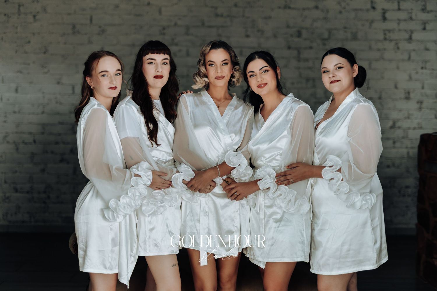 Group wearing matching white satin robes posing together in studio setting.