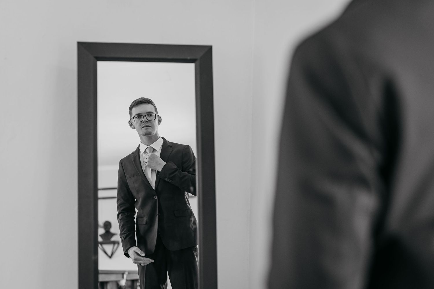 Black and white photo series showing a person in formal attire reflected in multiple mirrors creating a repeating pattern.