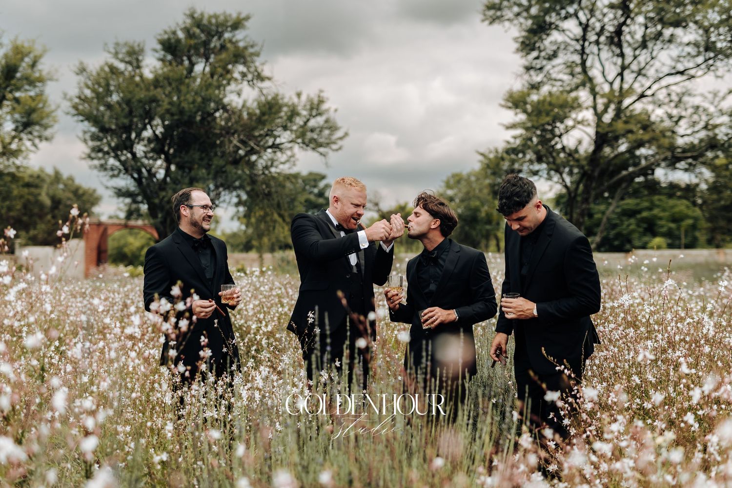 A group wearing black outfits stands together in a blooming cotton field on an overcast day.