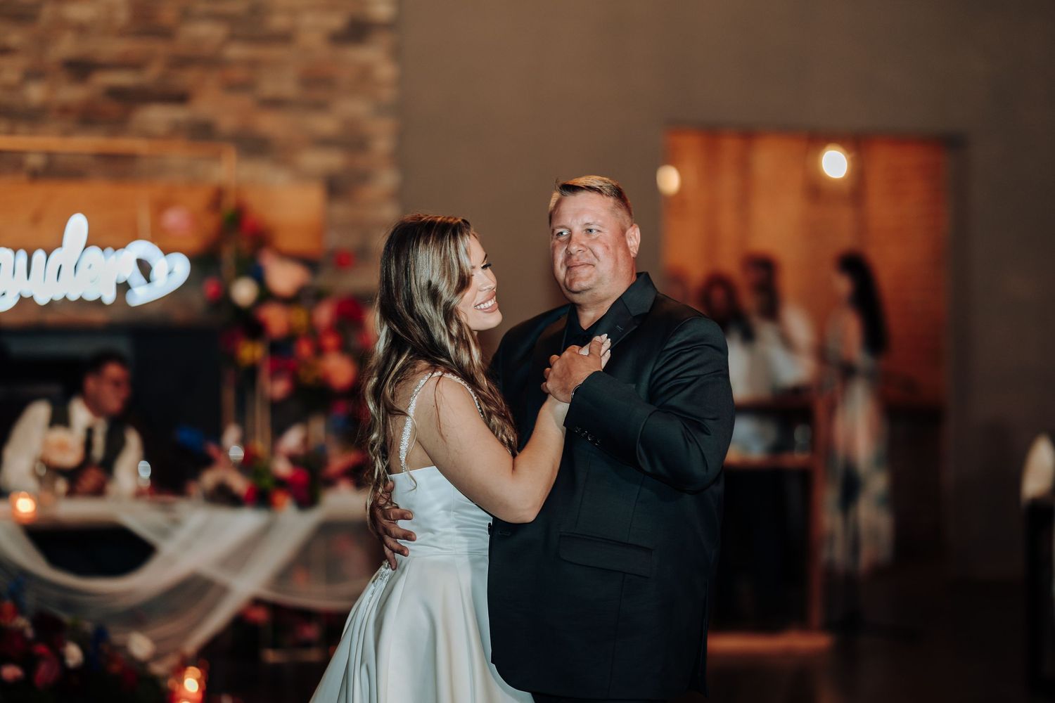 Wedding guests sharing dances during an evening reception with ambient lighting.