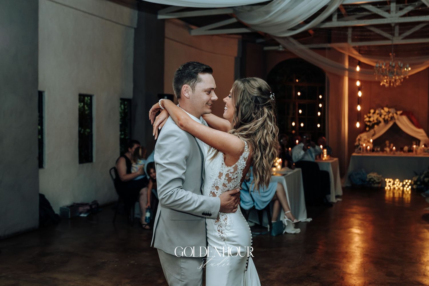 A romantic moment between newlyweds during their first dance at an indoor reception.