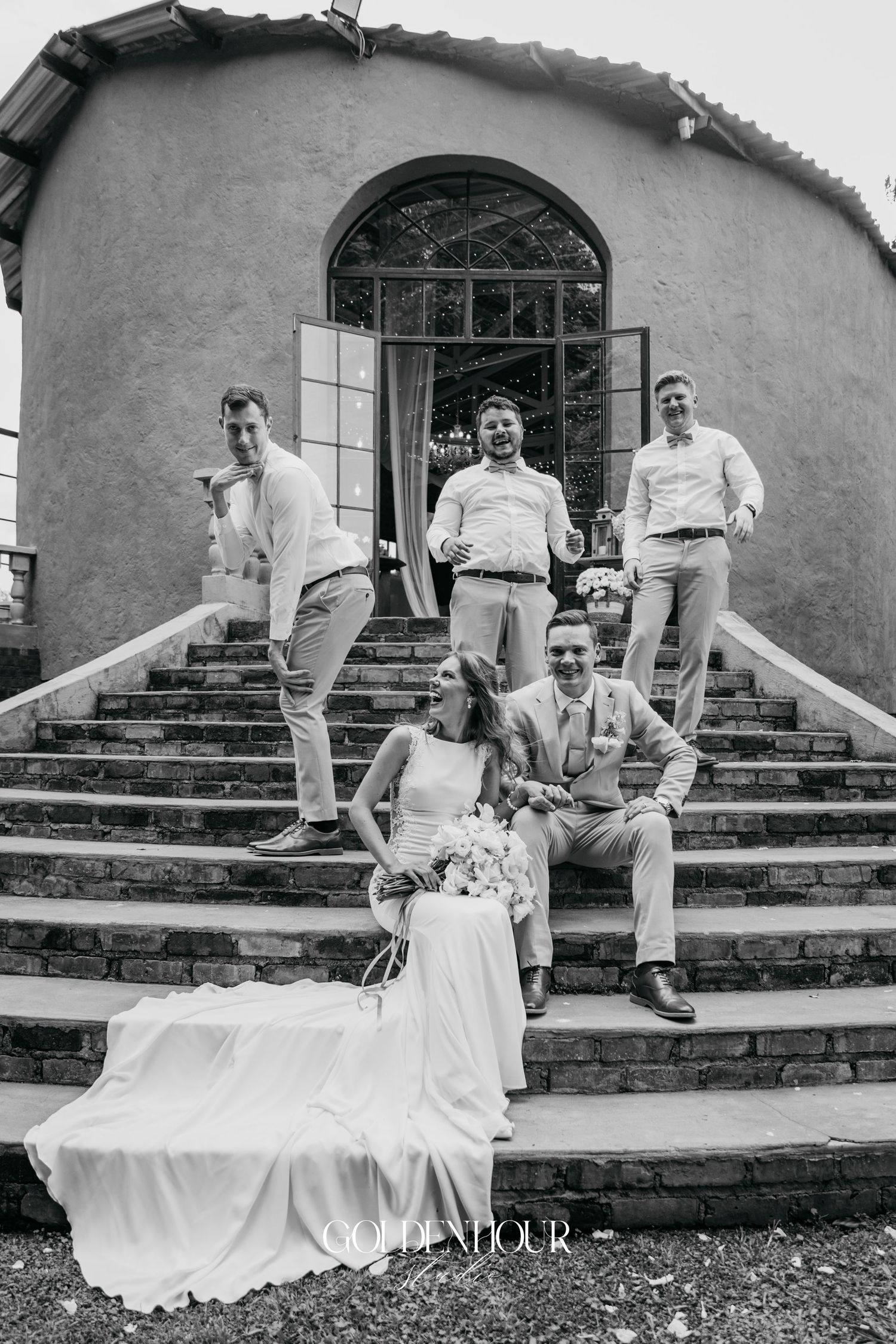 Fun wedding party photo sequence on stone steps showing groomsmen jumping in black and white.
