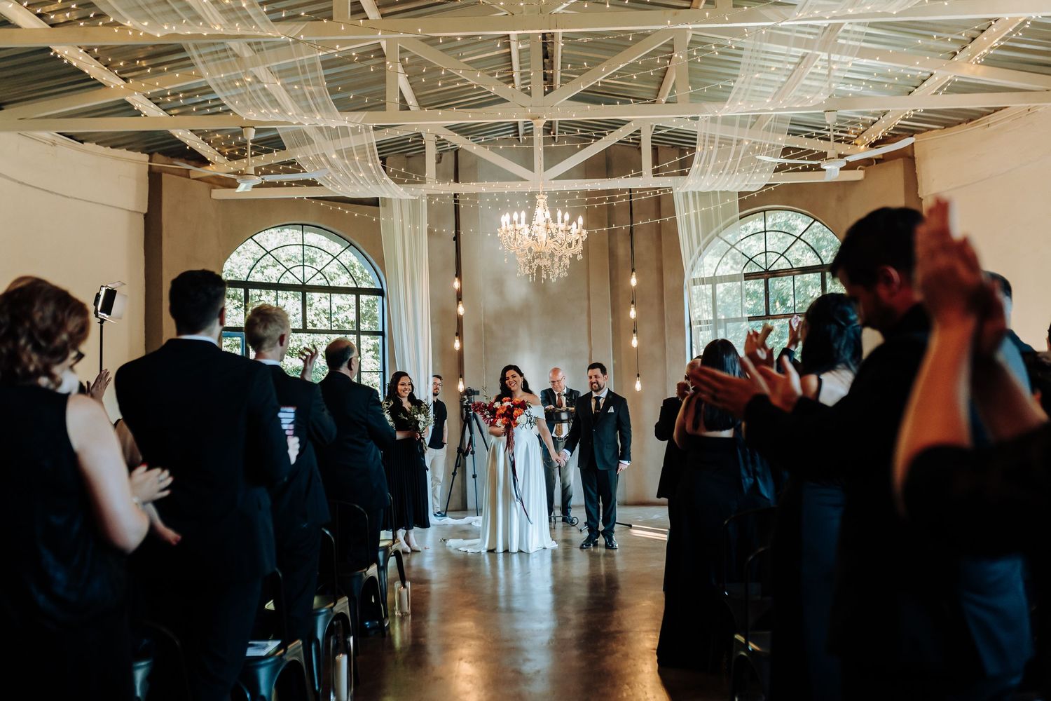 Elegant ballroom interior with chandelier and arched windows during an event gathering.