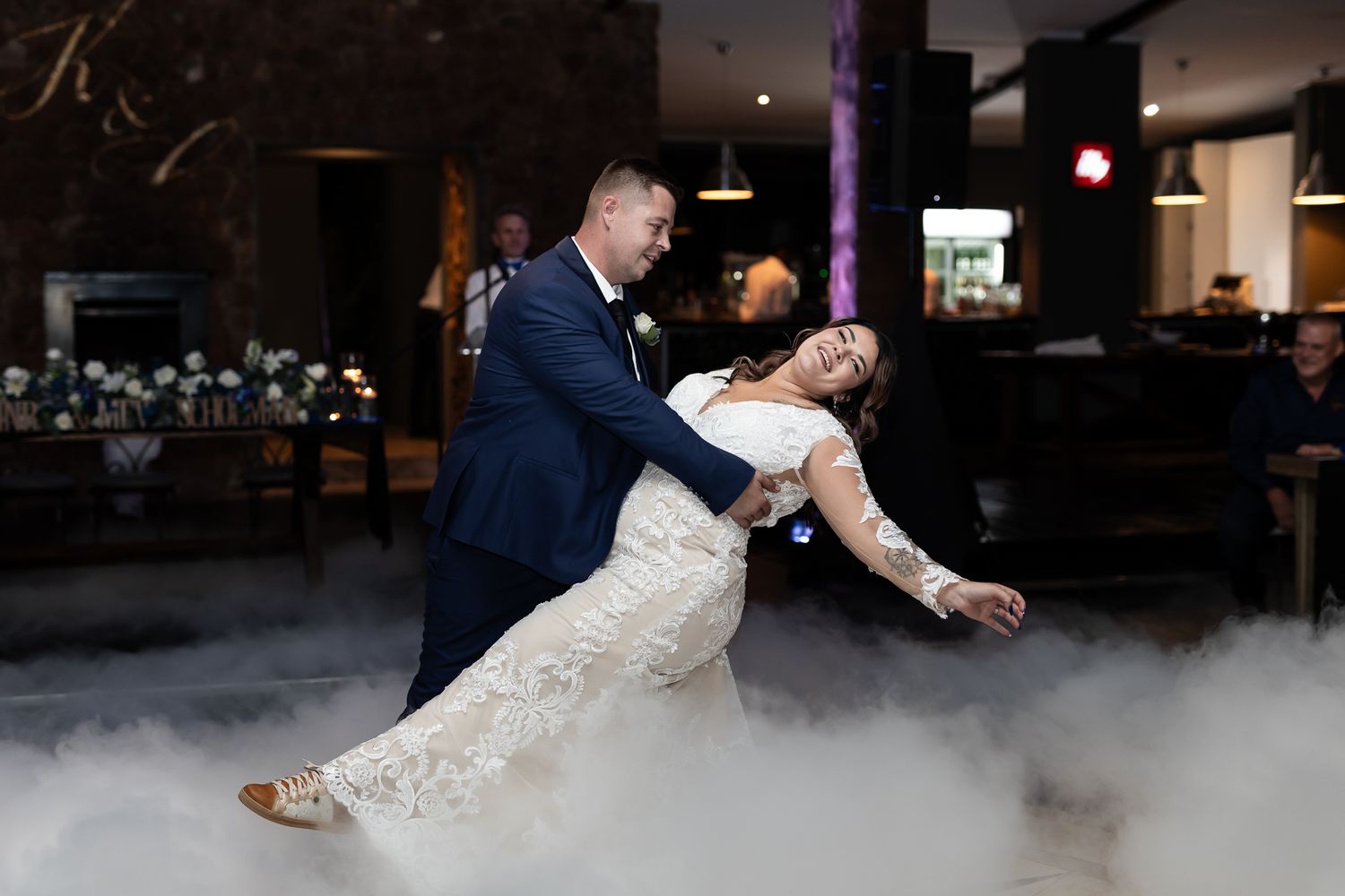 Couple performs dramatic dance dip on fog-covered dance floor with sparkler effects.