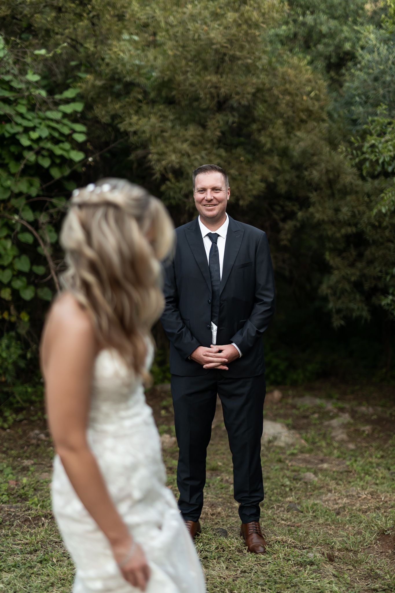 Romantic wedding portrait in a garden setting with natural foliage backdrop.
