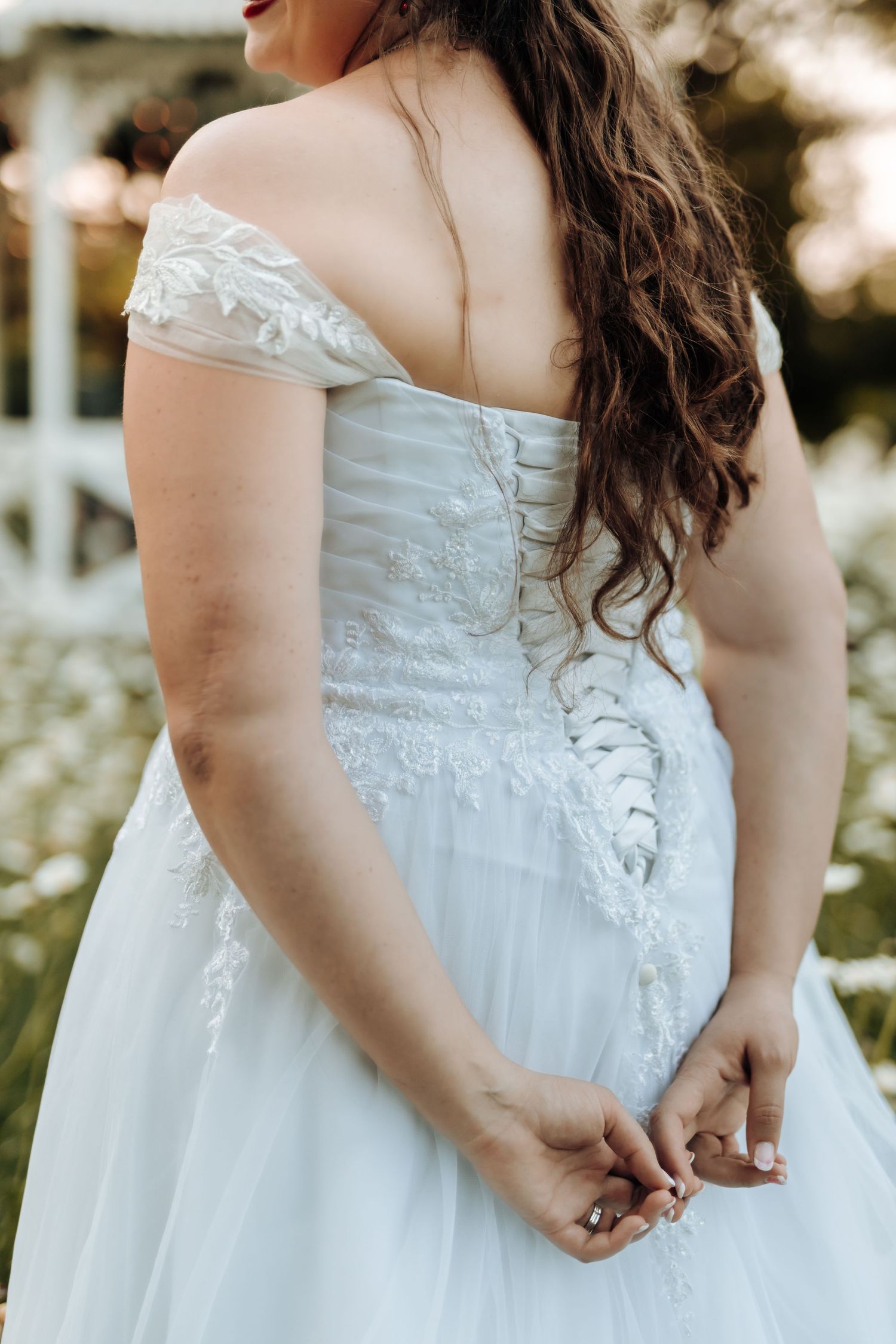 Close-up detail of intricate lace-up back on white wedding dress with delicate cap sleeves.